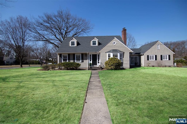 cape cod home with roof with shingles, a chimney, and a front lawn