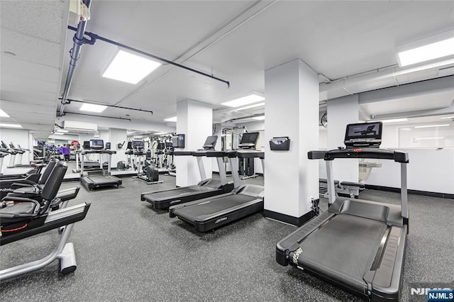 exercise room featuring an AC wall unit and baseboards