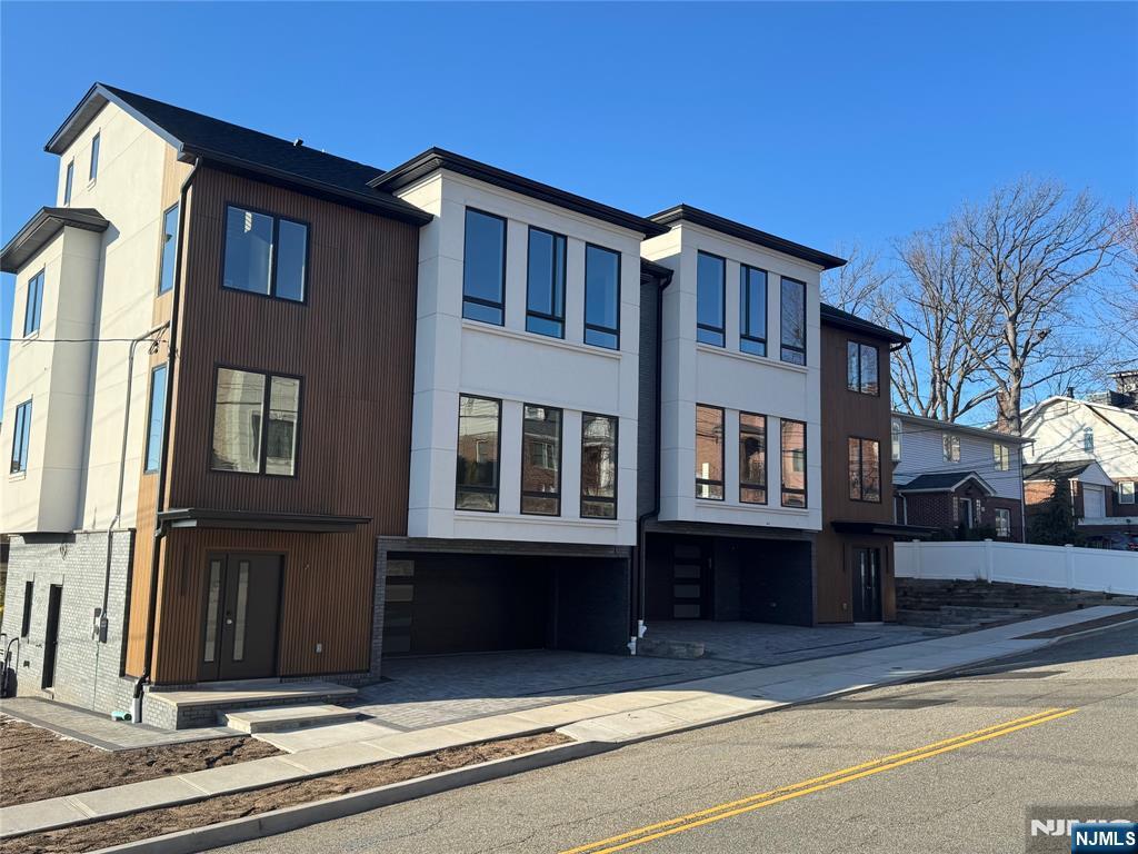 view of front facade featuring stucco siding, an attached garage, decorative driveway, and fence