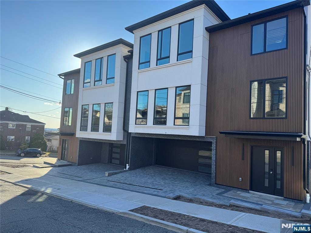 contemporary home featuring stucco siding, driveway, french doors, and a garage