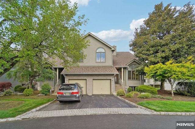 view of front of house featuring brick siding, aphalt driveway, roof with shingles, a chimney, and an attached garage