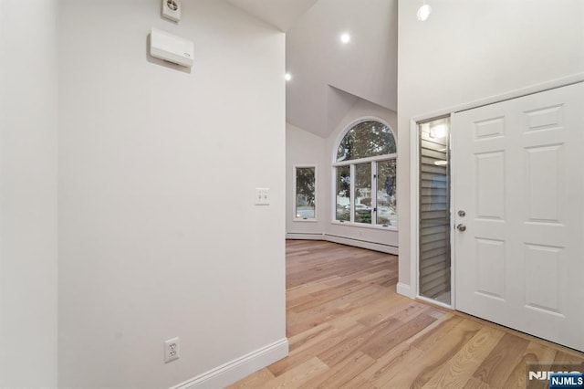 entryway featuring high vaulted ceiling, light wood-type flooring, baseboards, and a baseboard radiator