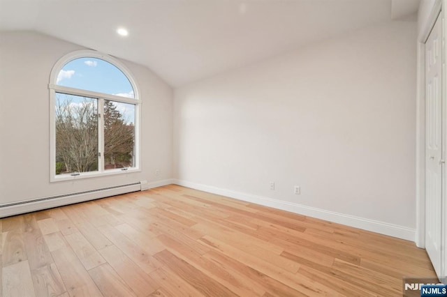 unfurnished room featuring light wood finished floors, baseboards, lofted ceiling, and a baseboard radiator