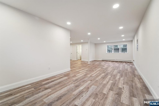 spare room featuring a baseboard heating unit, recessed lighting, baseboards, and light wood finished floors