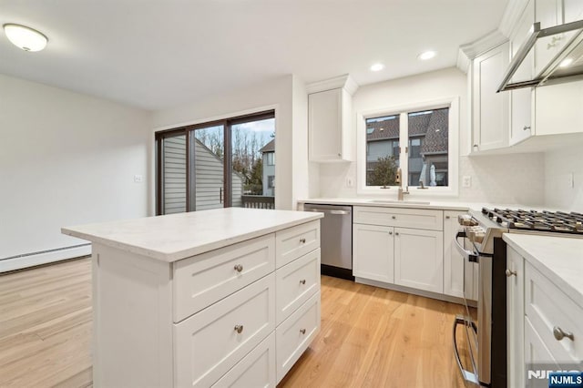 kitchen featuring a sink, under cabinet range hood, a kitchen island, appliances with stainless steel finishes, and light wood finished floors