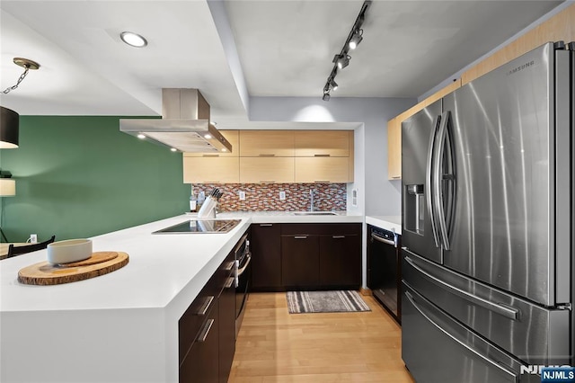 kitchen featuring light wood finished floors, a peninsula, black appliances, light countertops, and island range hood