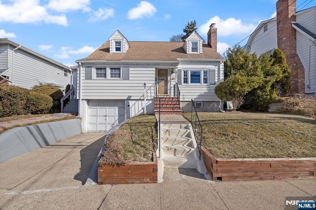 cape cod home with a front yard, driveway, an attached garage, a chimney, and a shingled roof