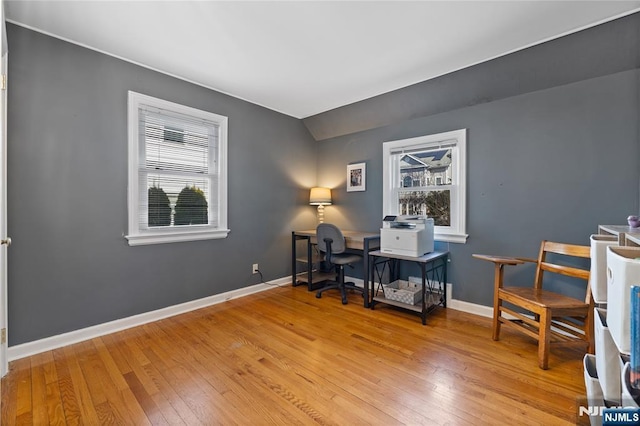 home office featuring vaulted ceiling, a healthy amount of sunlight, baseboards, and hardwood / wood-style flooring