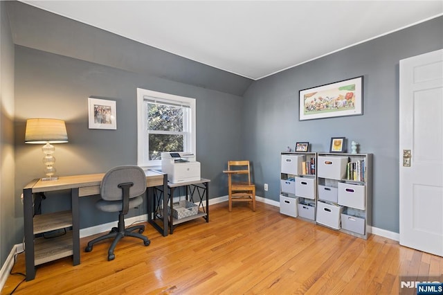 home office featuring baseboards, lofted ceiling, and light wood finished floors