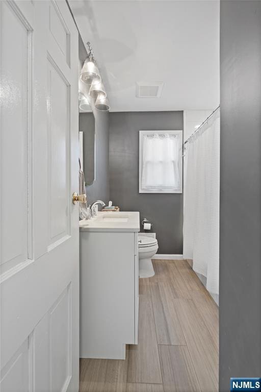 bathroom featuring vanity, a shower with curtain, wood finished floors, visible vents, and toilet