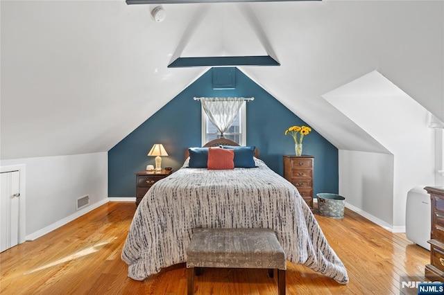 bedroom with visible vents, lofted ceiling, baseboards, and hardwood / wood-style floors