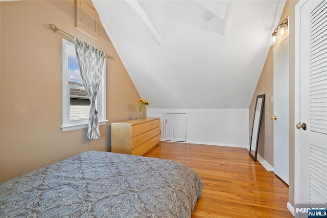 bedroom featuring baseboards, lofted ceiling, and wood finished floors