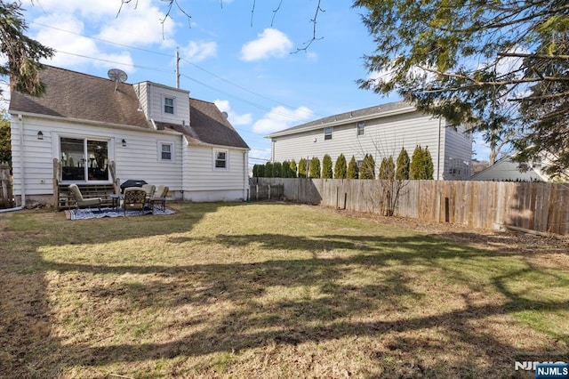 rear view of house with a yard, a fenced backyard, and a shingled roof