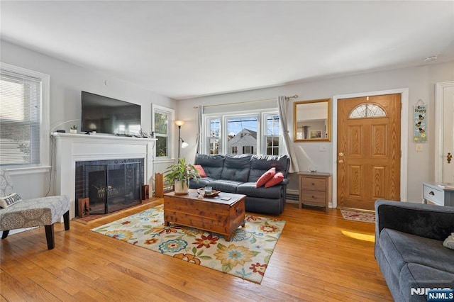 living room with light wood-style floors and a tiled fireplace