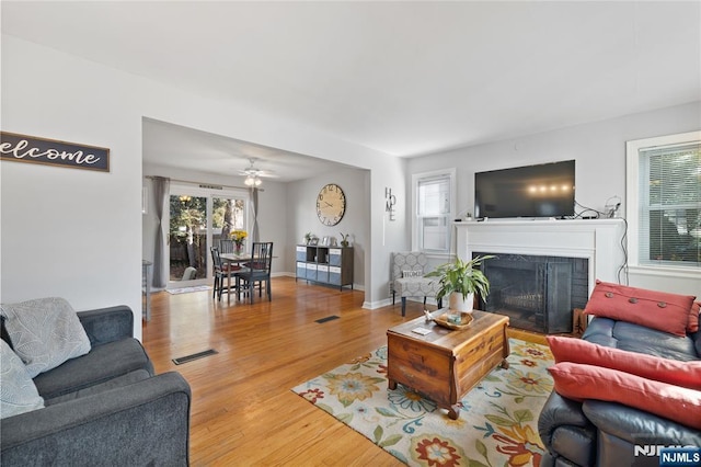 living room with visible vents, baseboards, wood finished floors, and a fireplace