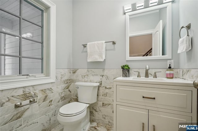 bathroom featuring a wainscoted wall, toilet, tile walls, and vanity