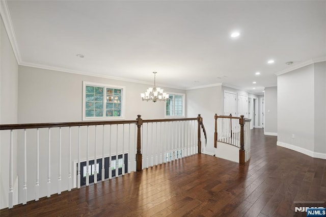 spare room featuring a notable chandelier, crown molding, baseboards, and hardwood / wood-style flooring