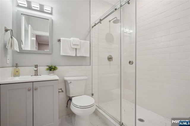 full bathroom with vanity, toilet, tile walls, and a shower stall