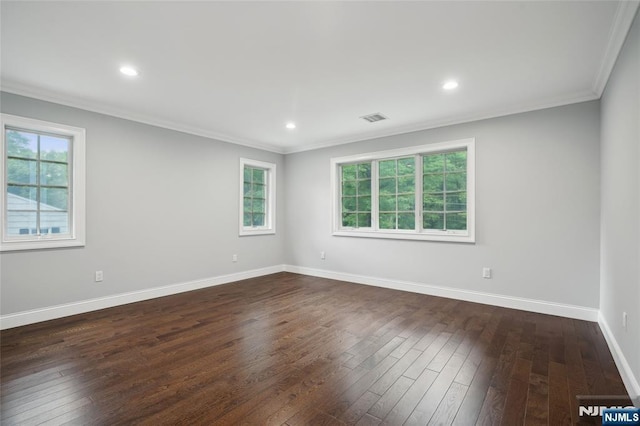 empty room featuring a wealth of natural light, visible vents, crown molding, baseboards, and dark wood-style flooring