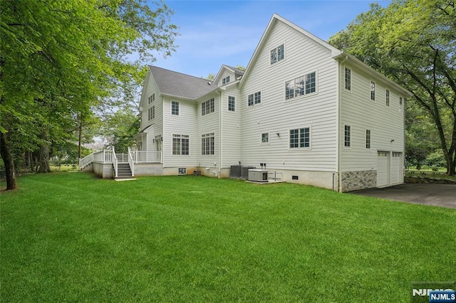 back of house with a yard, an attached garage, cooling unit, and driveway