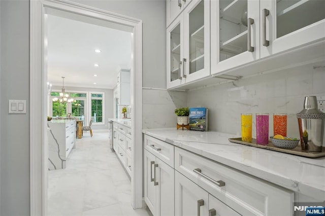 bar featuring tasteful backsplash, crown molding, recessed lighting, a notable chandelier, and marble finish floor