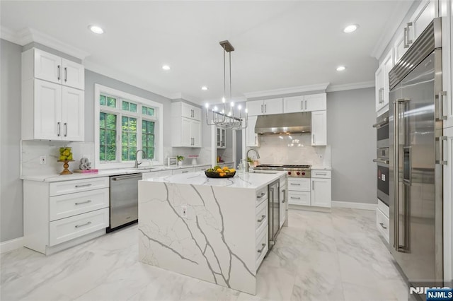 kitchen with under cabinet range hood, crown molding, marble finish floor, and appliances with stainless steel finishes