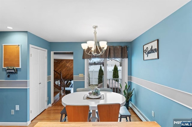 dining area featuring a baseboard heating unit, baseboards, wood finished floors, and a notable chandelier