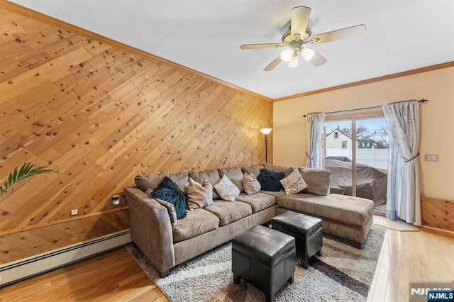 living room with a baseboard radiator, ornamental molding, light wood-style floors, a ceiling fan, and wooden walls