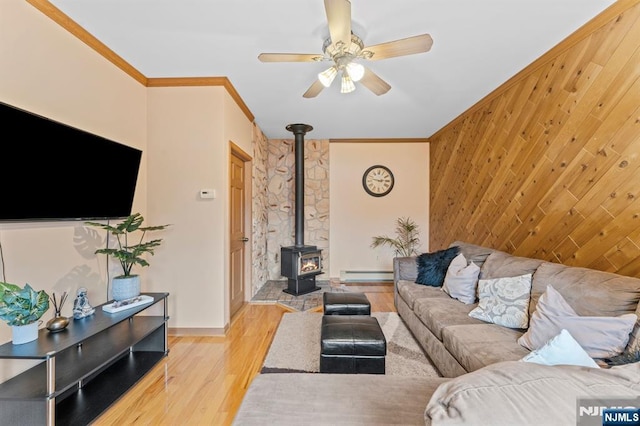 living area featuring crown molding, light wood finished floors, a baseboard radiator, an accent wall, and wooden walls