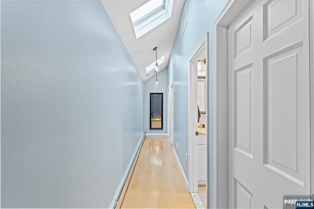 hallway featuring lofted ceiling with skylight, light wood-style flooring, and baseboards