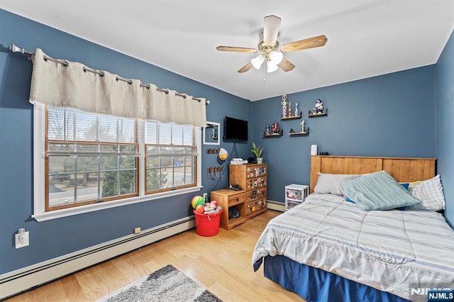 bedroom with a baseboard heating unit, ceiling fan, and wood finished floors