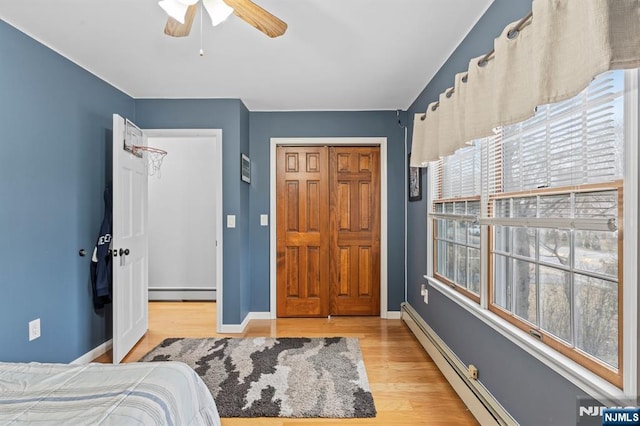 bedroom featuring baseboards, a baseboard radiator, a baseboard heating unit, and wood finished floors