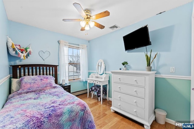 bedroom with a baseboard heating unit, baseboards, visible vents, and light wood-style floors