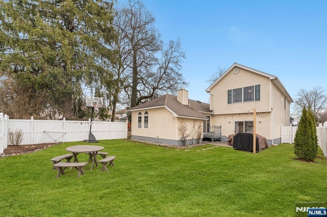 rear view of house with a yard, a chimney, and a fenced backyard