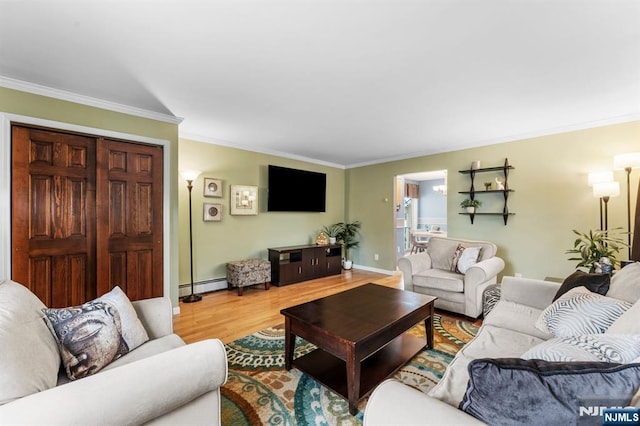 living area with a baseboard radiator, crown molding, baseboards, and wood finished floors