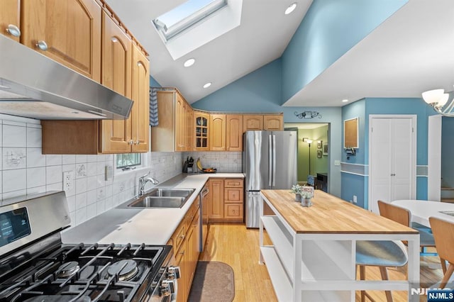 kitchen featuring vaulted ceiling with skylight, butcher block countertops, glass insert cabinets, stainless steel appliances, and under cabinet range hood