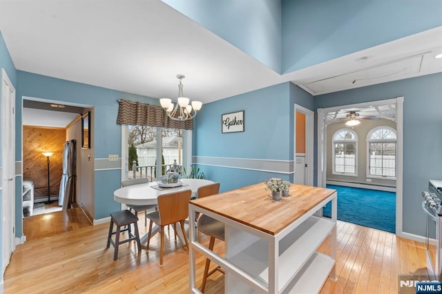 dining space featuring ceiling fan with notable chandelier, light wood-type flooring, baseboards, and a healthy amount of sunlight