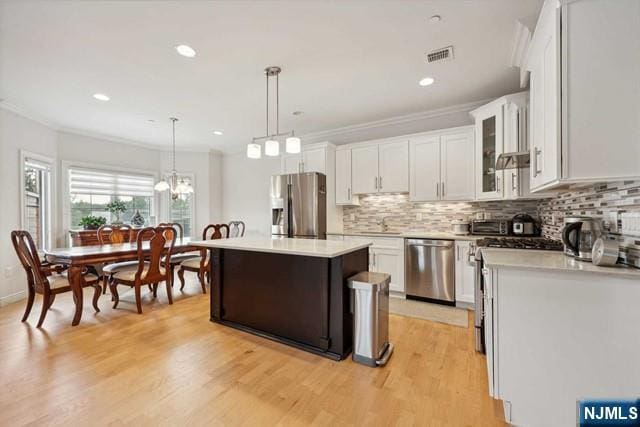 kitchen featuring stainless steel appliances, tasteful backsplash, light countertops, and white cabinetry