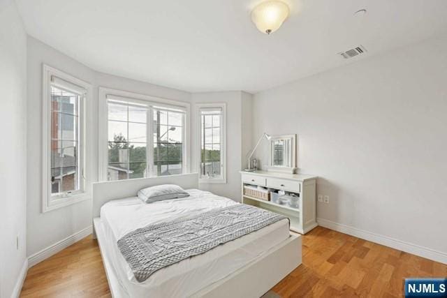 bedroom with light wood-type flooring, baseboards, and visible vents