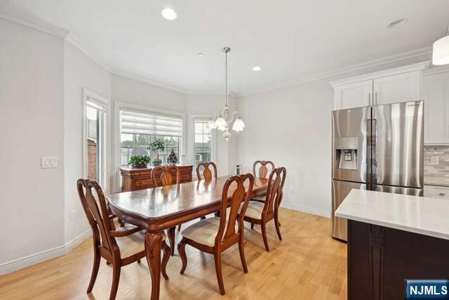 dining area with an inviting chandelier, baseboards, light wood finished floors, and crown molding