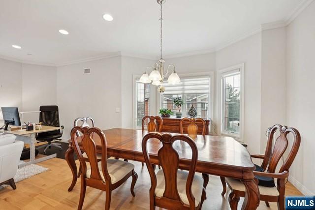 dining area featuring visible vents, light wood-style flooring, crown molding, a chandelier, and recessed lighting