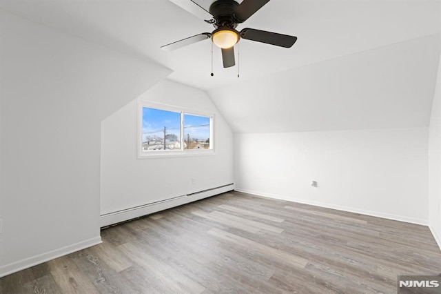 additional living space featuring a baseboard heating unit, ceiling fan, baseboards, lofted ceiling, and wood finished floors