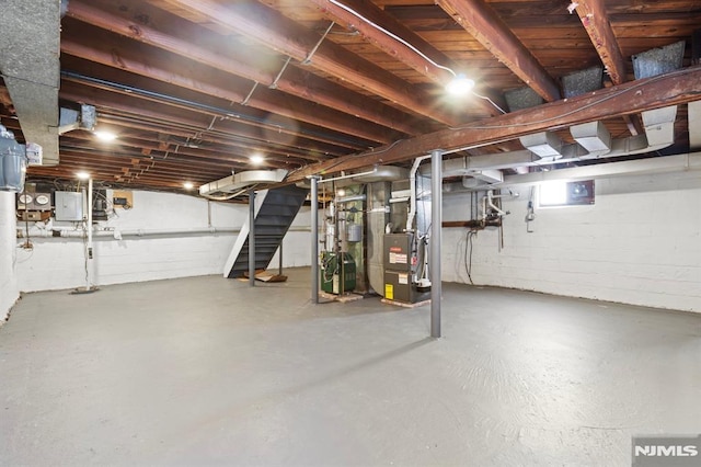 basement with stairs, electric panel, and heating unit