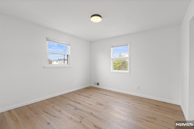 spare room featuring visible vents, baseboards, and light wood-style floors