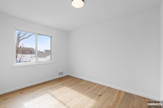 unfurnished room with visible vents, baseboards, and wood-type flooring