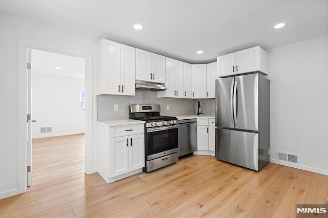 kitchen with under cabinet range hood, visible vents, stainless steel appliances, and light countertops