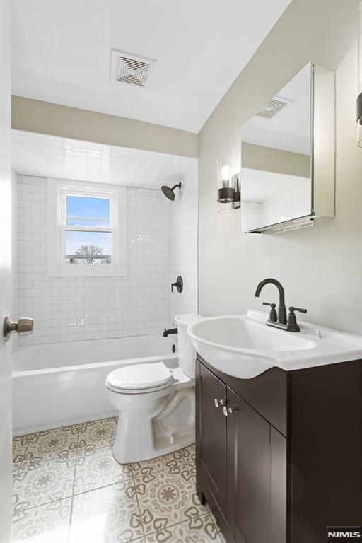 full bath featuring visible vents, toilet, vanity, tile patterned flooring, and shower / bathtub combination