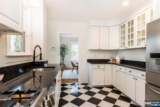 kitchen featuring glass insert cabinets, dark floors, stainless steel appliances, white cabinetry, and a sink