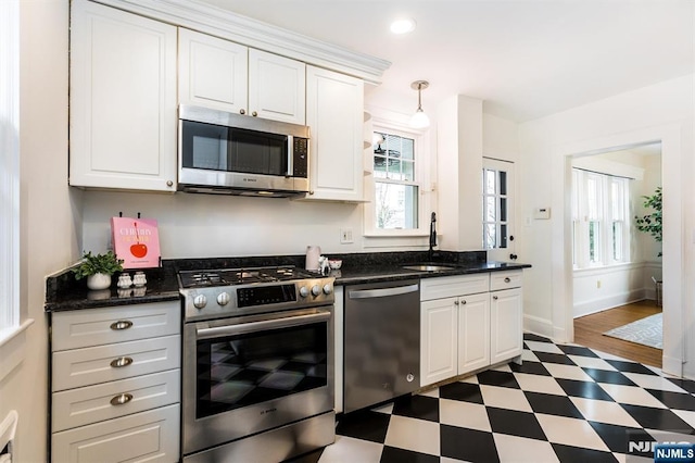 kitchen with a sink, stainless steel appliances, white cabinets, and tile patterned floors