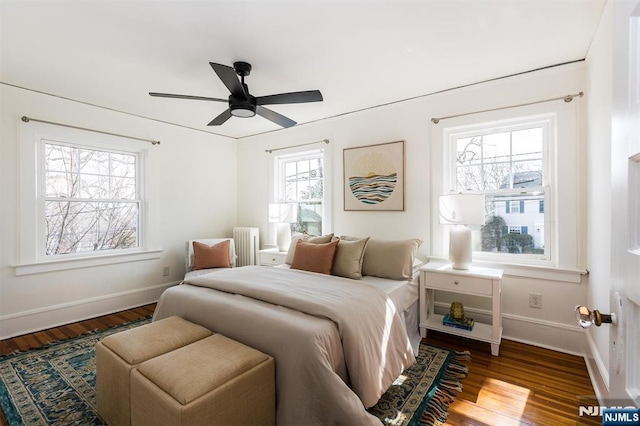 bedroom featuring radiator, wood finished floors, baseboards, and ceiling fan